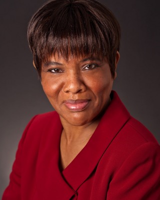 12-Theatrical-headshot-of-middle-aged-black-woman-with-short-hair-and-business-suit-on-dark-background-(Emile-Byron)