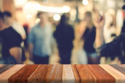 Brown wooden table with blurred abstract people on street background