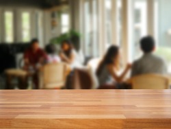 Empty wooden table and blurred people in cafe background